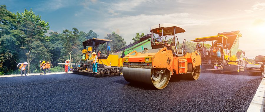 Construction site is laying new asphalt pavement, road construction workers and road construction machinery scene. Highway construction site scene.